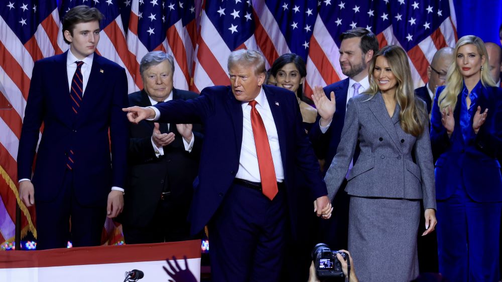 Donald Trump and his family and supporters on stage. Trump is pointing at the audience.